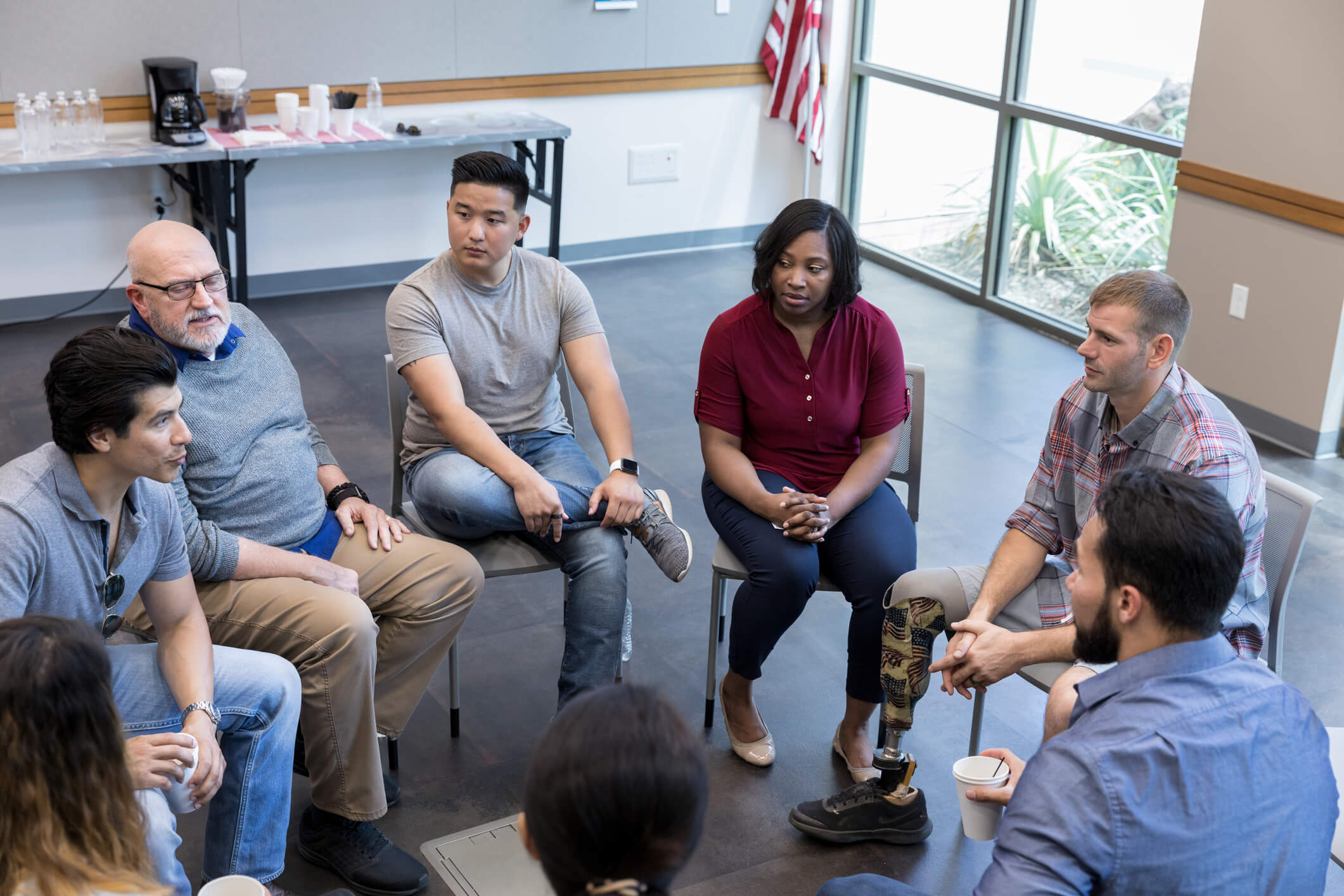 A diverse group of people participate in a 12-step recovery group.