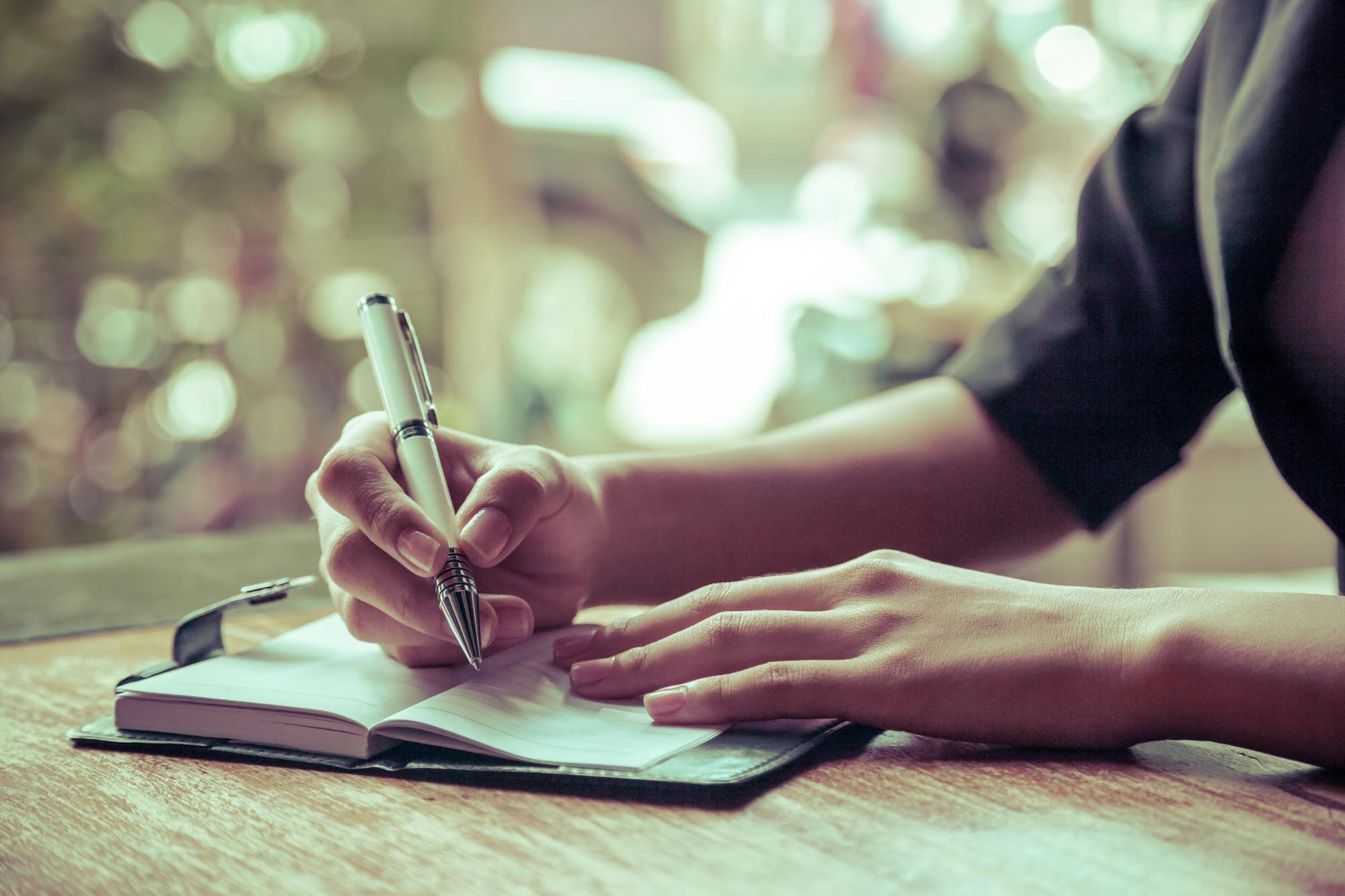 A man writing in a journal as form of self-care.