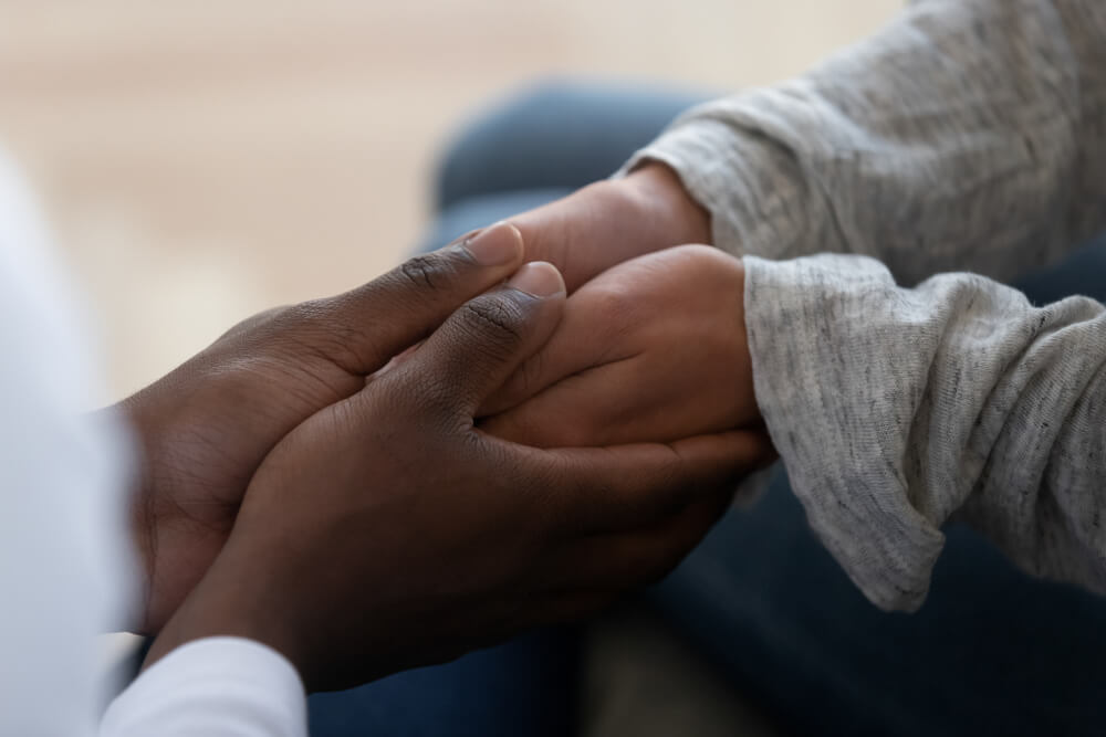 A person holds hands with a family member for comfort.